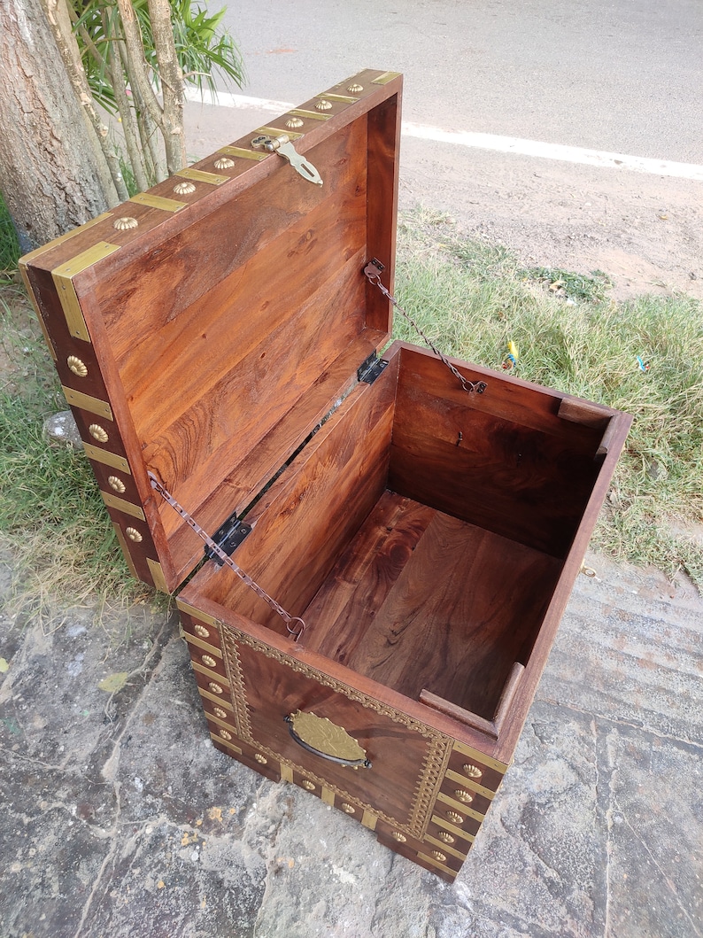 May include: A wooden storage chest with a hinged lid and brass accents. The chest is open and the interior is visible. The chest has a decorative brass handle on the front.