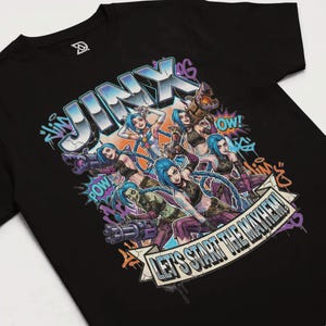 May include: Black t-shirt featuring a graphic of the character Jinx from the video game League of Legends. The design includes the word "Jinx" in large, stylized letters, along with multiple images of the character and the phrase "LET'S START THE MAYHEM!"