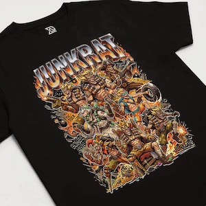 May include: Black t-shirt featuring a colorful graphic of multiple characters with weapons and the word "Junkrat" in a fiery font. The design includes the phrases "Tic-Tock" and "Bombs Away".
