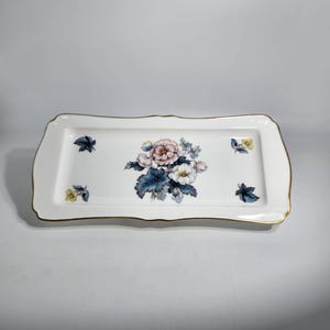 May include: A white rectangular serving tray with a gold rim and a floral design in shades of pink, blue, and yellow.