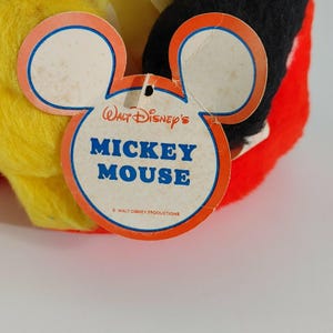 May include: A red, yellow, and black Mickey Mouse plush toy with a white tag that reads "Walt Disney's Mickey Mouse" and "&copy; WALT DISNEY PRODUCTIONS".