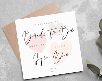 May include: A white card with pink hearts and the text "To the beautiful Bride to Be Georgina on your Hen Do Paris 2023".