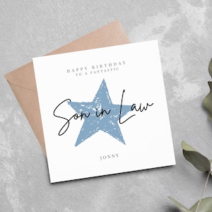 Könnte beinhalten: Eine weiße Karte mit einem blauen Stern und dem Text "Happy Birthday to a Fantastic Son in Law" und dem Namen "Jonny" unten.