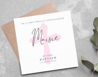May include: A white card with a pink cross and the text "To a very special goddaughter Maisie on your Baptism 12 June 2022".