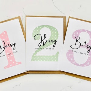 Op de afbeelding: Drie gepersonaliseerde verjaardagskaarten met een nummer, een naam en de tekst "Happy Birthday". De kaarten hebben een roze, groene en paarse achtergrond met een stippen- of sterrenpatroon.