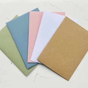May include: Five blank cards in different colors: green, blue, pink, white, and brown. The cards are arranged in a fan shape.