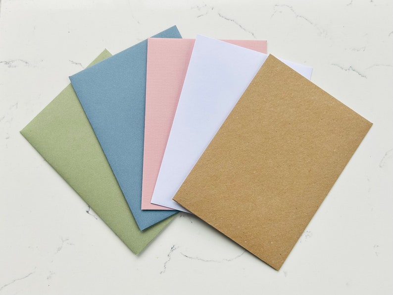 May include: Five blank cards in different colors: green, blue, pink, white, and brown. The cards are arranged in a fan shape.