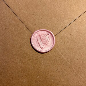 K&ouml;nnte beinhalten: Ein rosa Wachssiegel mit einem Herzmotiv.