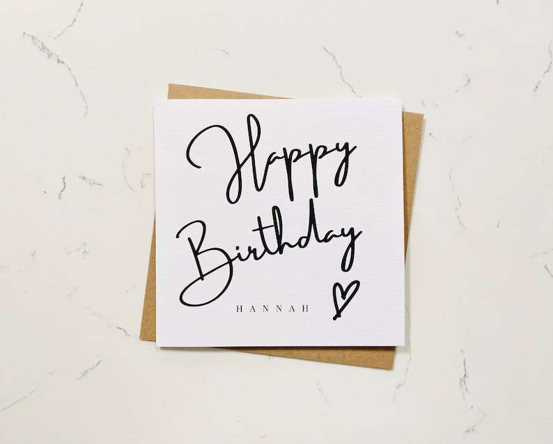 Puede incluir: Tarjeta blanca con escritura negra que dice "Feliz cumplea&ntilde;os Hannah" con un peque&ntilde;o s&iacute;mbolo de coraz&oacute;n.