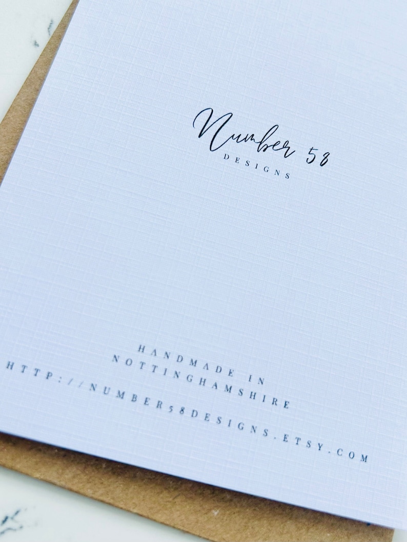 Puede incluir: Una tarjeta blanca con el texto "Number 58 Designs" en escritura cursiva negra. El texto "Handmade in Nottinghamshire" y la direcci&oacute;n del sitio web "http://number58designs.etsy.com" est&aacute;n impresos en negro debajo del logotipo.
