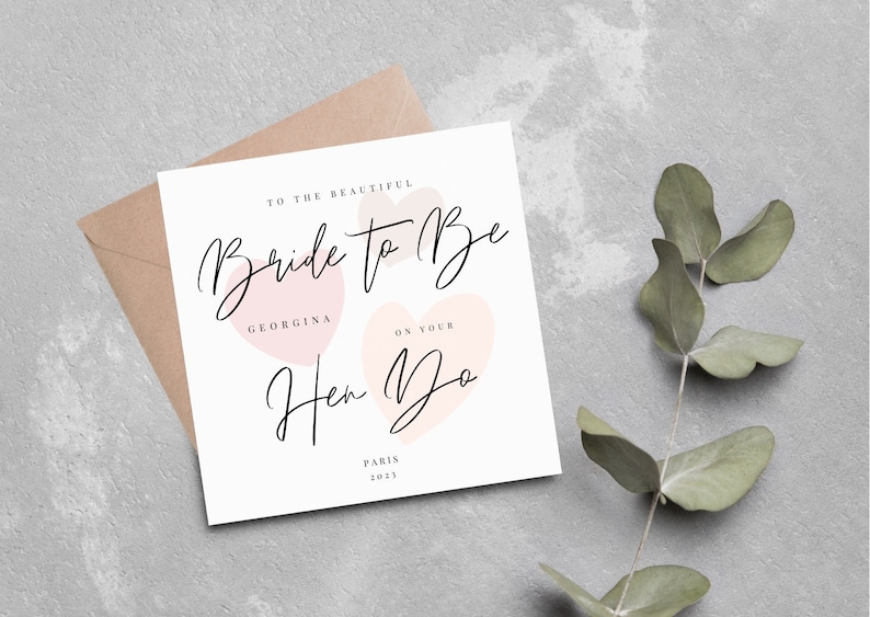 K&ouml;nnte beinhalten: Eine wei&szlig;e Karte mit rosa Herzen und dem Text "To the beautiful Bride to Be Georgina on your Hen Do Paris 2023".