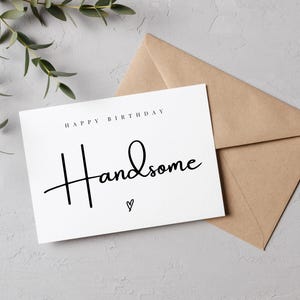 Könnte beinhalten: Weiße Karte mit schwarzem Text, der "Happy Birthday Handsome" lautet, mit einem kleinen Herzsymbol unter dem Text.