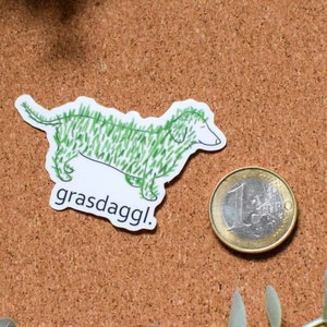 May include: A white sticker with a green cartoon dachshund with the text "grasdaggl!" printed below.