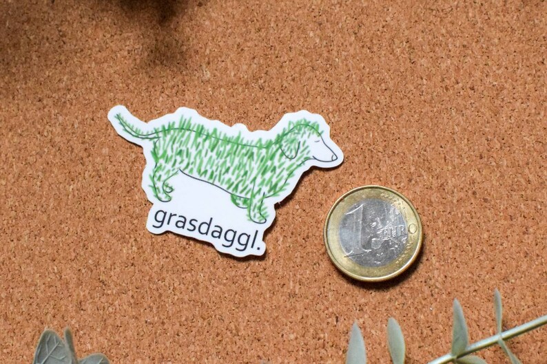 May include: A white sticker with a green cartoon dachshund with the text "grasdaggl!" printed below.