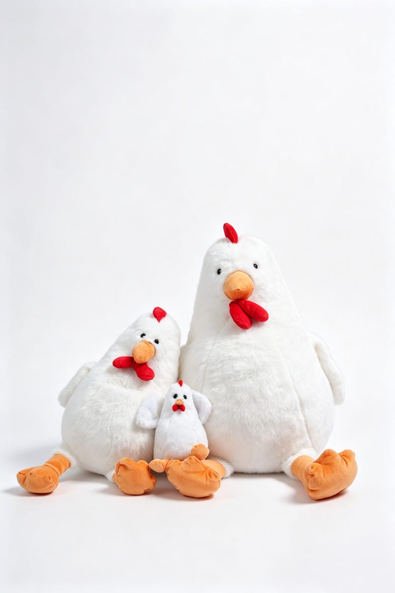 May include: Three plush chicken toys in varying sizes, each featuring soft white fur, bright orange beaks and feet, and a small red comb on top of the head. The figures are arranged in a group, with two larger chickens flanking a smaller chick.