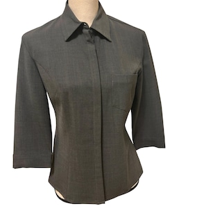 Op de afbeelding: Een grijs overhemd met knopen, driekwartmouwen en een enkele borstzak. Het overhemd wordt getoond op een mannequin, die de op maat gemaakte pasvorm en het klassieke ontwerp laat zien. De stof lijkt een geweven materiaal te zijn.