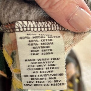 K&ouml;nnte beinhalten: Nahaufnahme eines Etiketts mit Text &uuml;ber Materialzusammensetzung und Pflegehinweise. Der Text lautet: 60% COTTON, 40% MODAL RAYON, 60% COTON, 40% MODAL, RAYONNE, RN# 66170, CAN 32054. Waschhinweise: HANDW&Auml;SCHE KALT, NUR CHLORFREIE BLEICHE VERWENDEN, NICHT VERDREHEN/AUSWRINGEN.