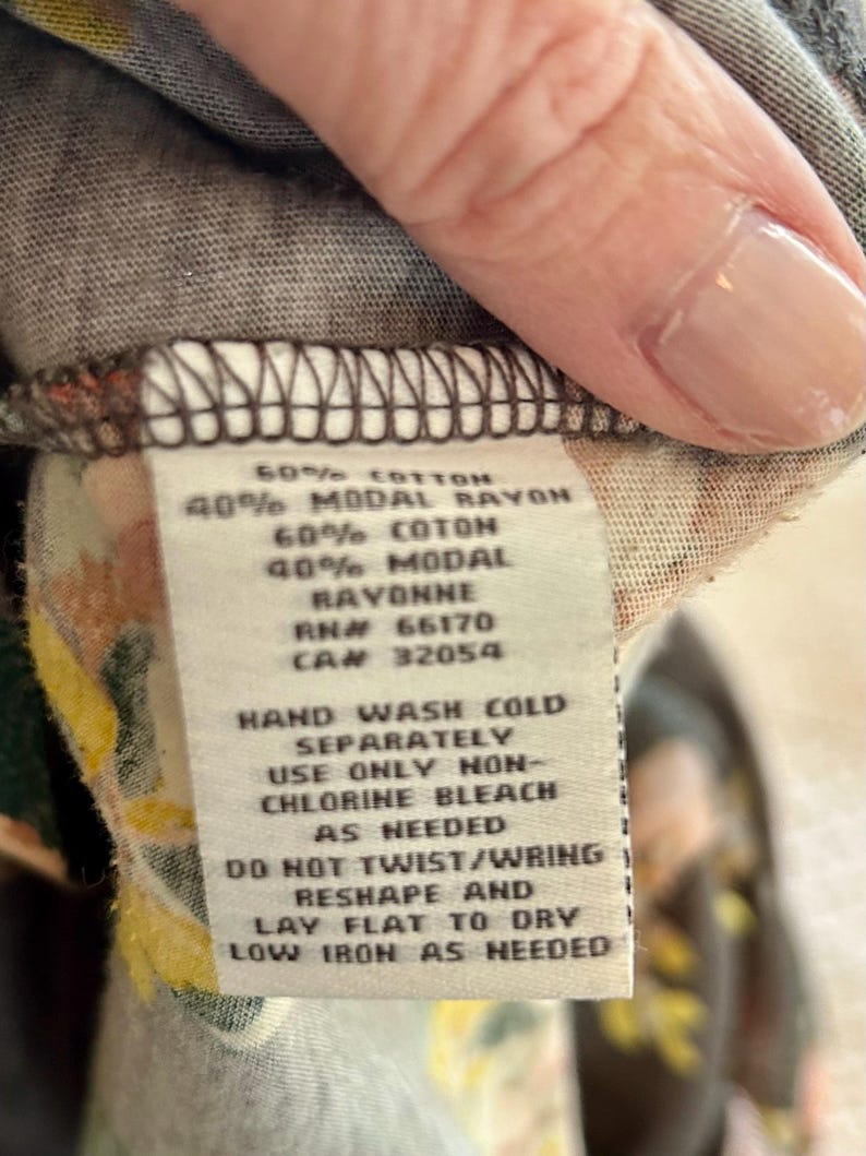 K&ouml;nnte beinhalten: Nahaufnahme eines Etiketts mit Text &uuml;ber Materialzusammensetzung und Pflegehinweise. Der Text lautet: 60% COTTON, 40% MODAL RAYON, 60% COTON, 40% MODAL, RAYONNE, RN# 66170, CAN 32054. Waschhinweise: HANDW&Auml;SCHE KALT, NUR CHLORFREIE BLEICHE VERWENDEN, NICHT VERDREHEN/AUSWRINGEN.