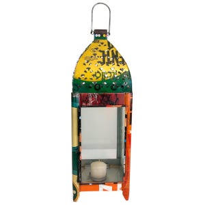 May include: A colorful metal lantern with a handle. The lantern has a yellow, green, and orange design with cut-out patterns. A white candle sits inside the glass-paneled interior. The lantern is made of recycled materials.