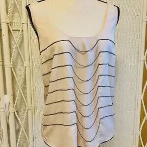 May include: A sleeveless, light pink top with a scoop neck and a layered design. The layers are outlined with a dark gray trim. The top is displayed on a mannequin.