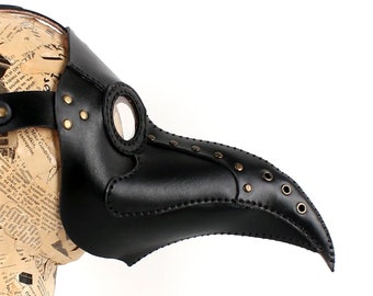 May include: A black leather plague doctor mask with a long beak and a round eye piece. The mask has a strap for wearing.