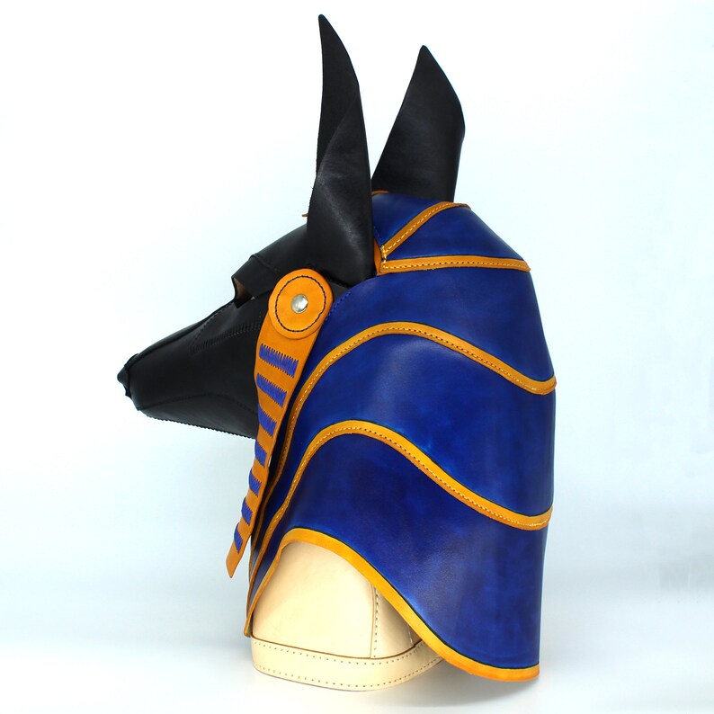 May include: A blue and black leather Anubis mask with gold stitching. The mask has a pointed snout and large ears.
