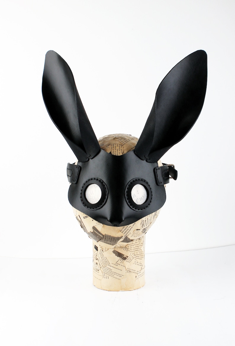 Peut inclure: Masque de lapin en cuir noir avec de grandes oreilles et des trous ronds pour les yeux. Le masque est sur une t&ecirc;te de mannequin.