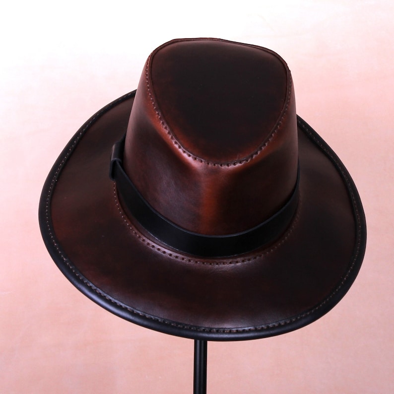 May include: A brown leather fedora hat with a wide brim and a black leather band.