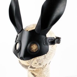 Peut inclure: Masque de lapin en cuir noir avec de grandes oreilles et deux trous ronds pour les yeux. Le masque est dot&eacute; d'une sangle pour le fixer &agrave; la t&ecirc;te.