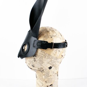 Peut inclure: Masque de lapin en cuir noir avec de longues oreilles et une sangle. Le masque est sur une t&ecirc;te de mannequin.