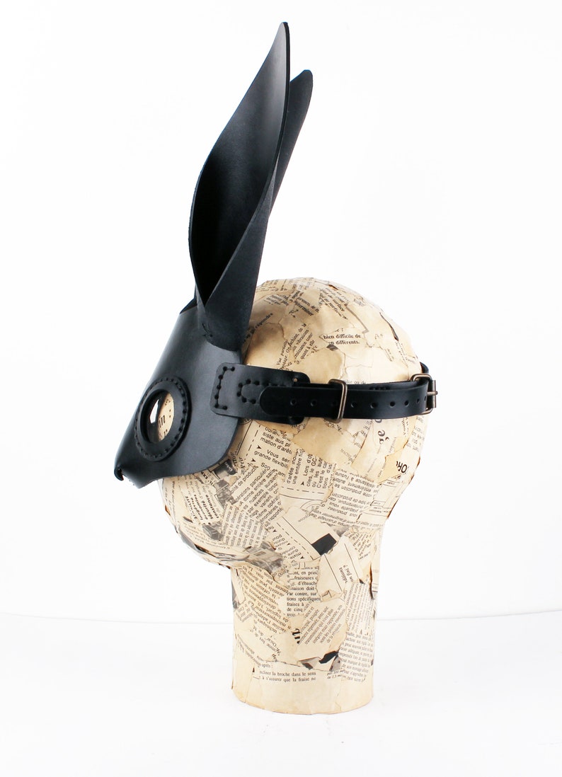 Peut inclure: Masque de lapin en cuir noir avec de longues oreilles et une sangle. Le masque est sur une t&ecirc;te de mannequin.