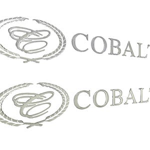 May include: Two silver-colored emblems. Each emblem features a stylized letter "E" inside a laurel wreath, with the word "COBALT" in a matching silver font. The background is plain white.
