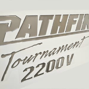 May include: Silver Pathfinder Tournament 2200V boat decal. The decal has a raised, 3D effect.