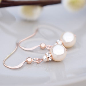 May include: Rose gold earrings with a pearl and crystal accents.
