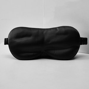 Op de afbeelding: Een zwart satijnen slaapmasker met een elastisch bandje.
