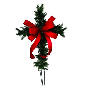 May include: A green artificial Christmas tree shaped like a cross with a large red bow.