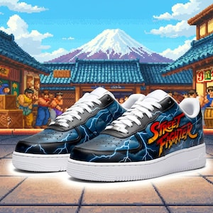 Può includere: Un paio di scarpe da ginnastica Street Fighter blu e nere con suole e lacci bianchi. Le scarpe da ginnastica presentano un design a fulmine e il logo Street Fighter in rosso e giallo. Lo sfondo è una scena di strada giapponese pixelata.