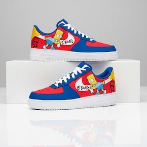 Puede incluir: Un par de zapatillas rojas, azules y amarillas con suelas blancas. Las zapatillas presentan un diseño de personaje de dibujos animados con el texto "El Barto" en el lateral. Los zapatos se exhiben sobre una superficie blanca.