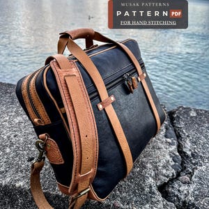 May include: A black leather briefcase with tan leather straps, a top handle, and a detachable shoulder strap. The bag features a zippered main compartment and a front pocket. A label at the top reads MUSAK PATTERNS PATTERN PDF FOR HAND STITCHING.