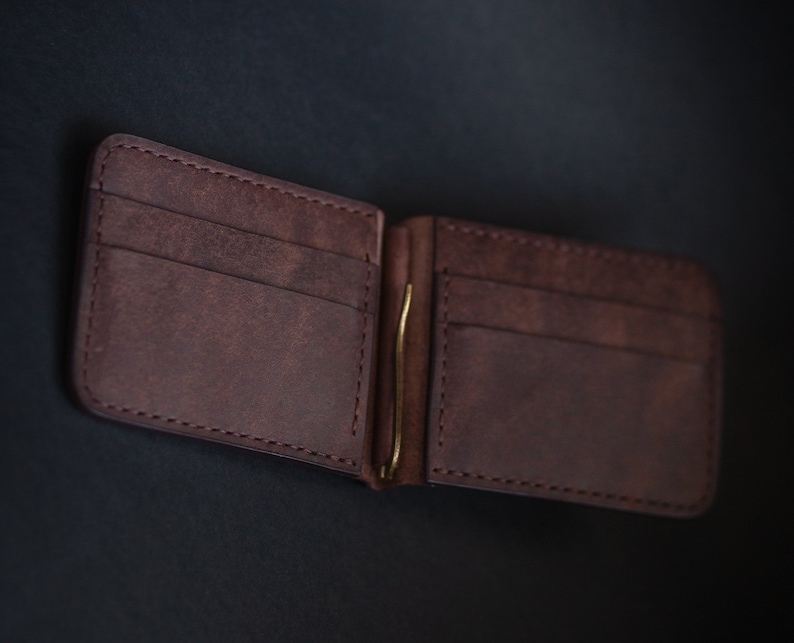May include: A brown leather wallet with a money clip. The wallet has multiple card slots and a fold-over design.