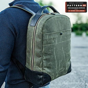 May include: An olive green waxed canvas backpack with black leather accents, a top handle, and a front pocket with a snap button. The bag features gold-tone zips and adjustable shoulder straps. Text reads: MUSAK PATTERNS PATTERN PDF FOR MACHINE SEWING 2 SIZES INCLUDED.