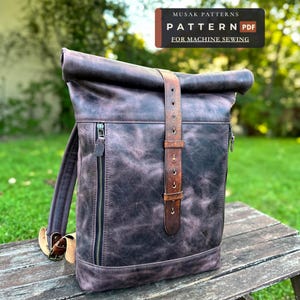 Può includere: Uno zaino roll-top marrone scuro con una texture effetto pelle invecchiata, dotato di una cerniera frontale verticale, un cinturino centrale con fibbia e spallacci regolabili. L'immagine include il testo MUSAK PATTERNS PATTERN PDF FOR MACHINE SEWING.