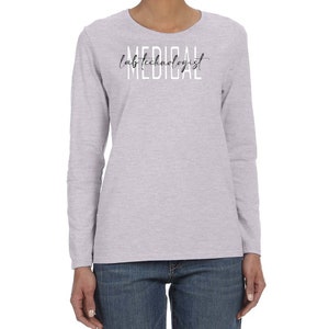 May include: A heather grey long-sleeve t-shirt with the text "lab technologist" written in black script above the word "MEDICAL" in white letters.