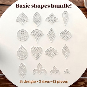 Op de afbeelding: Een verzameling van 42 heldere acryl basisvormontwerpen, waaronder druppels, harten en geometrische patronen. De vormen zijn gerangschikt op een wit oppervlak, met de tekst "Basic shapes bundle!" en "14 designs • 3 sizes • 42 pieces."