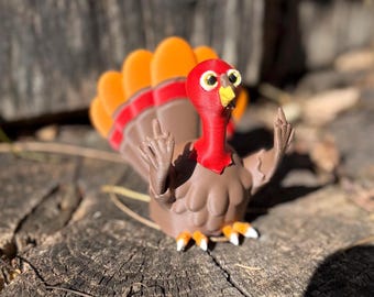 May include: A brown and red turkey figurine with orange feathers giving the middle finger with both hands.