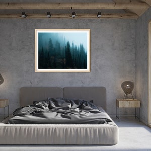 May include: A framed landscape art print of a misty forest scene hangs above a bed with gray bedding. The room has a modern design with concrete walls, wooden accents, and a large window.