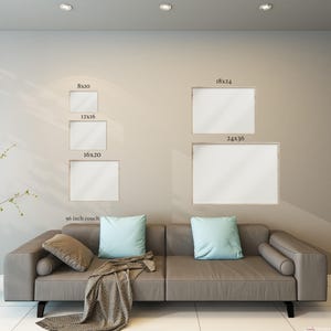Pu&ograve; includere: Una scena di soggiorno moderno con un divano grigio, cuscini blu e beige e una coperta. Sopra il divano, opere d'arte incorniciate di varie dimensioni (20x25, 30x41, 41x51, 46x61 e 61x91 cm) sono esposte su una parete neutra.