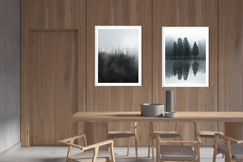 May include: Two framed black and white photographs of trees and reflections in water hanging on a wood wall above a wooden table with chairs.