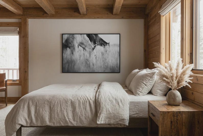Pu&ograve; includere: Una camera da letto con una tavolozza di colori neutri. Un letto con piumino e cuscini beige &egrave; al centro. Una stampa incorniciata in bianco e nero di cavalli al pascolo nell'erba alta &egrave; appesa sopra il letto. Un comodino in legno contiene un vaso di pampas.