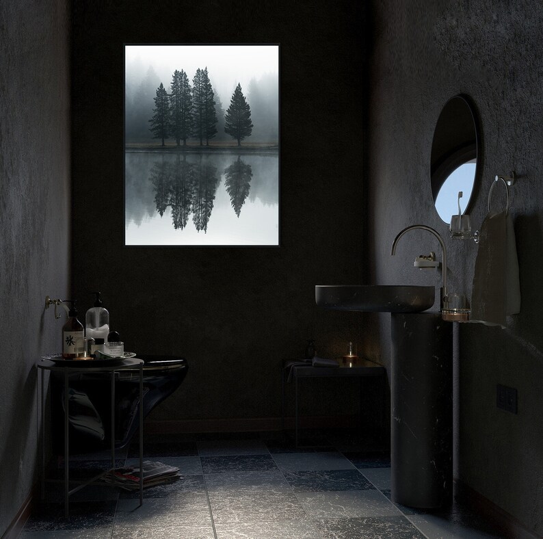 May include: A black bathroom vanity with a round sink and a black pedestal. The vanity is in front of a window with a view of a foggy forest. There are toiletries on a small table next to the vanity.